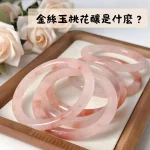 金絲玉桃花釀手鐲，淡粉色半透明玉鐲置於木盤中，呈現桃花釀柔和色調。